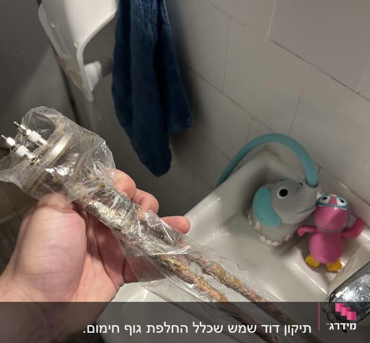 גוף חימום של דוד שמש מוחזק ביד מעל כיור